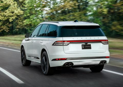A white 2025 Lincoln Aviator® SUV is being driven away down a road lined with colorful trees. | Johnson Brothers Lincoln in Temple TX