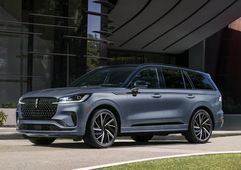 A gray 2025 Lincoln Aviator® SUV is parked outside a modern building showcasing the driver’s side of the vehicle. | Johnson Brothers Lincoln in Temple TX