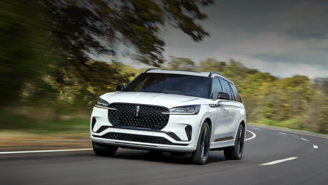 A white 2025 Lincoln Aviator® SUV is being driven down a road lined with trees. | Johnson Brothers Lincoln in Temple TX