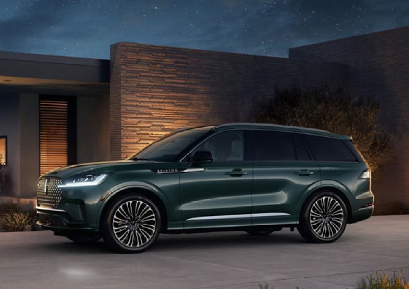 A green 2027 Lincoln Aviator® SUV is parked outside a contemporary home. | Johnson Brothers Lincoln in Temple TX