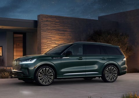 A green 2027 Lincoln Aviator® SUV is parked outside a contemporary home. | Johnson Brothers Lincoln in Temple TX