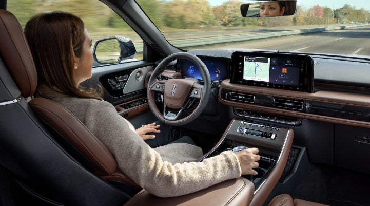 A 2027 Lincoln Aviator® SUV is being driven hands-free on a highway lined with trees. | Johnson Brothers Lincoln in Temple TX