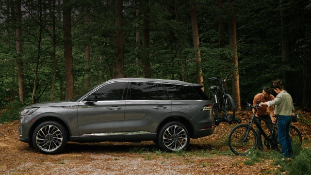 A father and son load e-bikes on a bike rack attached to a 2027 Lincoln Aviator® SUV. | Johnson Brothers Lincoln in Temple TX