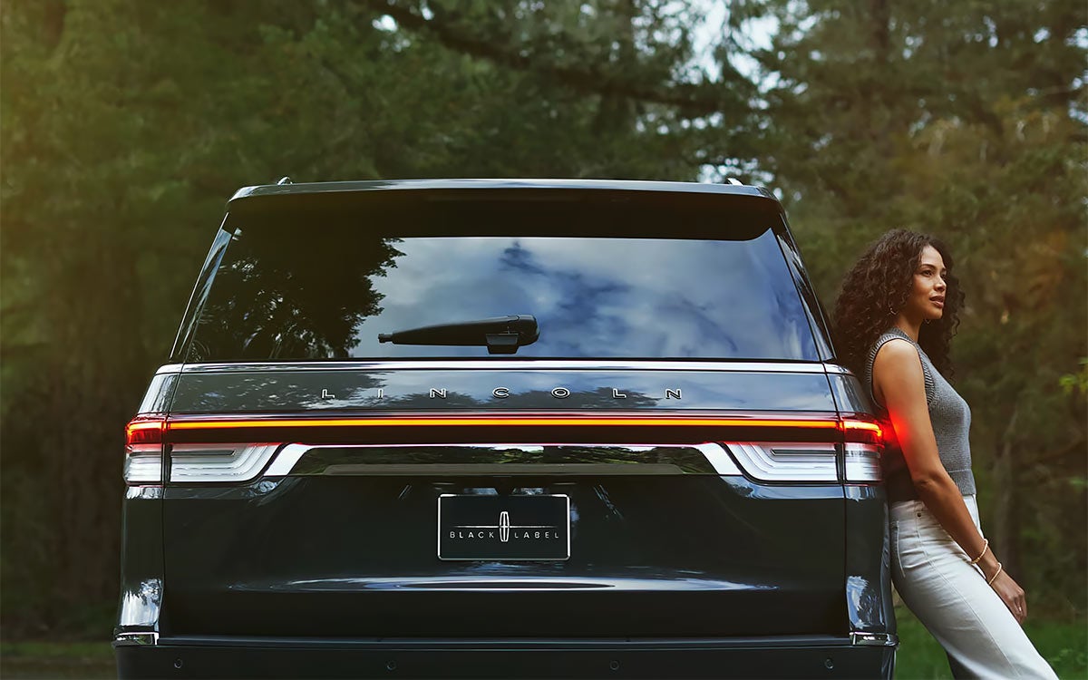 A woman leaning against the Lincoln Navigator® SUV.